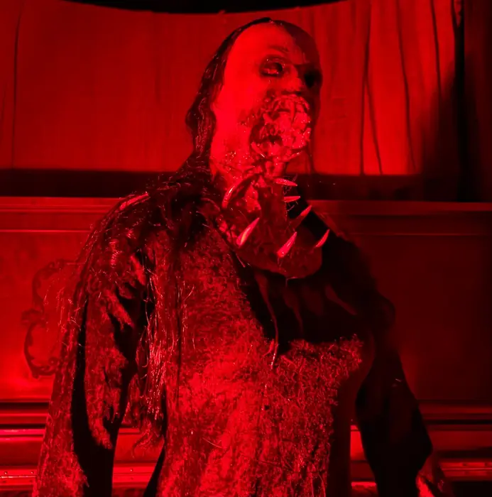 A Grimm Grounds horror character illuminated in red light