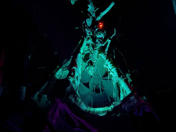 A towering Wendigo Trail figure illuminated in eerie green light