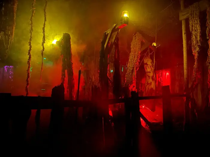 A fog-filled Grimm Grounds path illuminated in red and yellow
