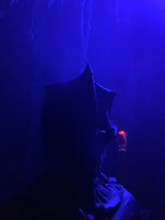 A hidden figure with glowing red eyes in blue fog